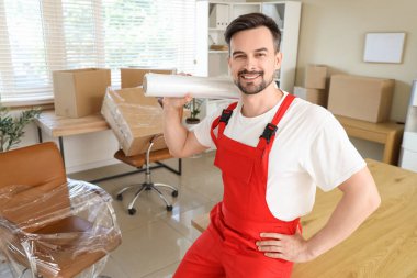 Ofisinde streç film rulosu olan erkek işçi.