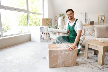 Erkek işçi ambalaj kutusu ve odada streç film