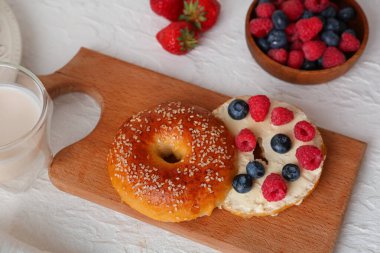 Beyaz arka planda tereyağlı ve böğürtlenli ahşap simit tahtası