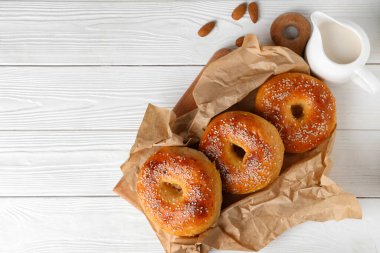 Lezzetli simit ve beyaz ahşap arka planda badem fıstığı olan kağıt fırını.