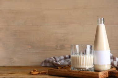 Bir bardak taze badem sütü ve ahşap kaplama fındıklı.