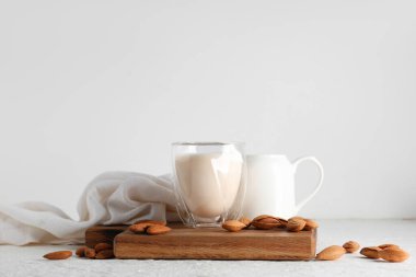 Beyaz arka planda fındıklı bir bardak taze badem sütü.