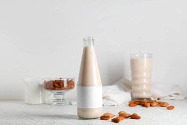 Beyaz arka planda fındık ve bir şişe taze badem sütü.