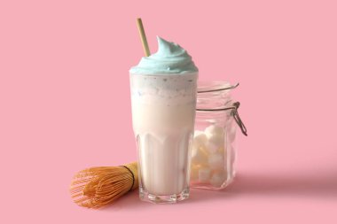 Bir bardak mavi dalgona matcha latte, rafine şekerli kavanoz ve pembe arka planda chasen.