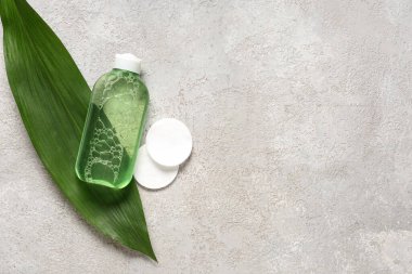 Bir şişe deniz suyu, yeşil yaprak ve arka planda pamuk pedleri.