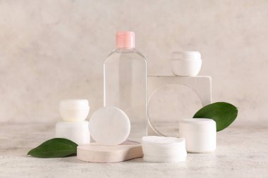 Bir şişe mikiler suyu, yeşil yapraklar, alçı tezgahları ve arka planda pamuk pedleri.