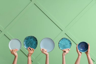 Yeşil arkaplanda boş tabakları tutan eller