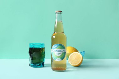 Turkuaz arka planda limonlu bir şişe ve bir bardak lezzetli kombu çayı.