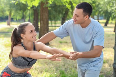 Park 'ta kişisel antrenörle antrenman yapan genç bir bayan.