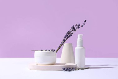 Farklı kozmetik ürünleriyle dekoratif podyumlar ve renkli arka planda lavanta çiçekleri