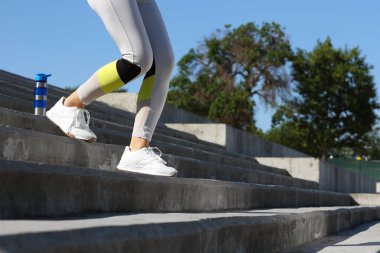 Bir şişe suyla genç Asyalı kadın stadyumda koşuyor, yakın plan.