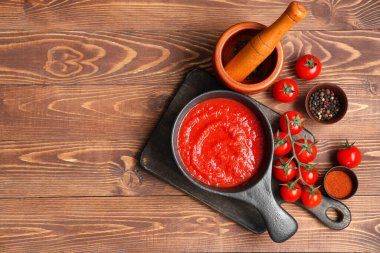 Ahşap arka planda biberli domates sosu ve kase kızartma tavası.