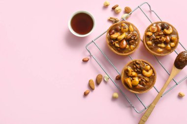 Fındık ve karamel soslu lezzetli tartlar pembe arka planda duruyor.