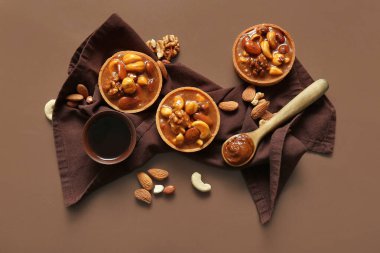 Kahverengi arka planda fındıklı ve karamel soslu lezzetli tartlar.