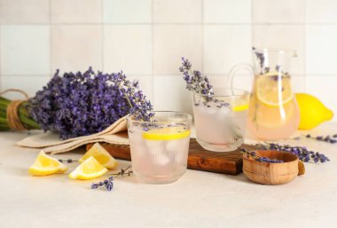 Çiçekli taze lavantalı limonata ve beyaz masada limon dilimi.
