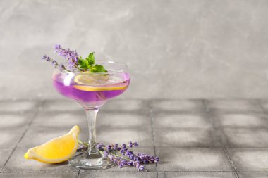 Bir bardak taze lavantalı limonata, nane ve gri fayanslı çiçekler.