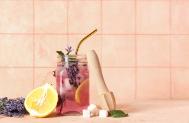 Mason kavanozu taze lavanta limonata, nane ve ahşap sıkacağı bej masa üzerinde.