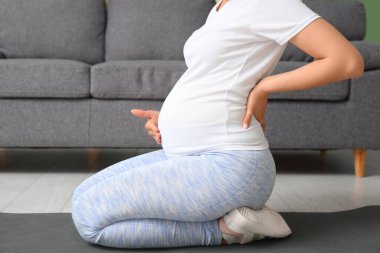 Güzel hamile kadın oturma odasında yoga yapıyor.