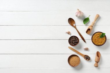 Tohumlu, biberli, fesleğenli ve sarımsaklı bir kase Dijon hardalı beyaz ahşap arka planda.