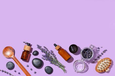 Leylak arka planında, lavanta yağı, çiçek ve spa taşları.