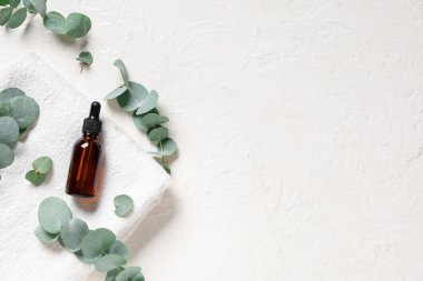 Hafif arkaplanda havlu ve bir şişe okaliptüs yağı.