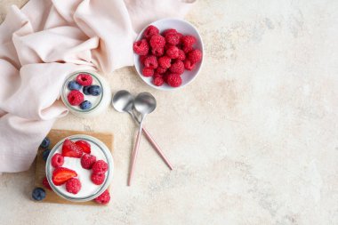 Beyaz arka planda farklı taze böğürtlenli lezzetli yoğurt kavanozları