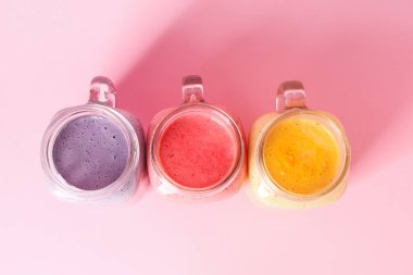 Mason kavanozları pembe arka planda farklı taze smoothie