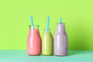 Renkli arka planda farklı taze smoothie şişeleri