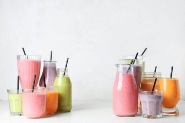 Beyaz arka planda farklı taze smoothie bardakları ve şişeleri