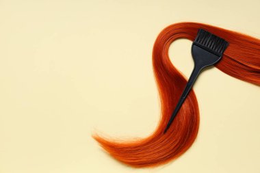 Kırmızı saç teli ve bej arka planda fırça