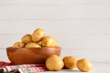 Beyaz masada çiğ patatesli ahşap kase.