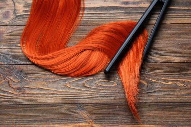 Kızıl saç teli ve tahta arka planda düzeltici demir.