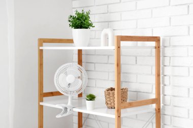 Oturma odasındaki raflarda modern elektrikli vantilatör.