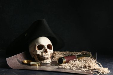 Korsan şapkalı kafatası, pusula ve dürbün haritada karanlık arka planda