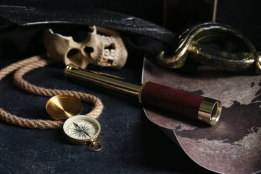 Karanlık masa üzerinde dürbünlü pusula ve harita, yakın plan. Korsan konsepti