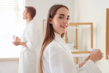 Banyoda duş aldıktan sonra krema dolu kavanozu olan genç bir kadın, yakın plan.