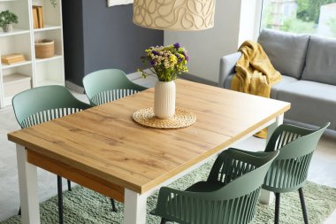 Yemek masasının üstünde kır çiçekleri olan vazo.