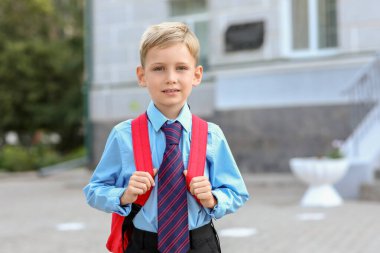 Okulun yanında sırt çantalı şirin bir çocuk.