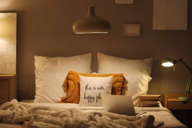 Geceleri karanlık yatak odasında bir yığın kitabın olduğu dizüstü bilgisayar.