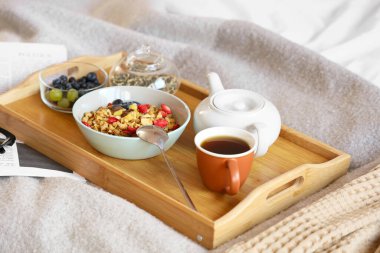 Yatak odasında kahvaltıda mısır gevreği, çay ve meyve tepsisi. Yakın çekim.