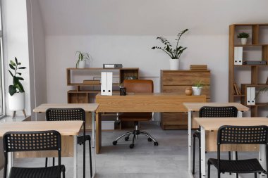 Sandalyeleri ve masası olan boş, şık bir sınıfın içinde.