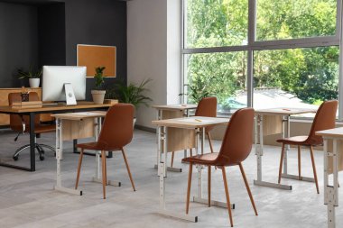 Modern sınıfta sınav için hazırlanmış sandalyeli okul masaları.