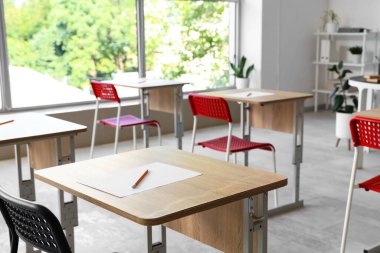 Boş sınıftaki masada bir sayfa kağıt ve kalem. Yakın çekim.