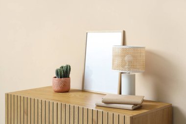 Tahta dolap, kitaplar, kaktüs ve bej duvarın yanında masa lambası.