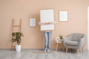 Oturma odasında boş çerçeveli genç bir kadın.