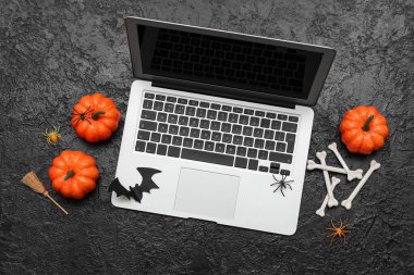 Karanlık arka planda Cadılar Bayramı kutlamaları için modern dizüstü bilgisayar ve dekor kompozisyonu