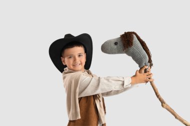 Hafif arka planda oyuncak atı olan şirin bir kovboy.