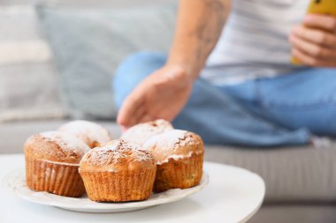 Genç adam evdeki masadan lezzetli kekleri alıyor, yakın plan.
