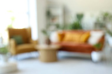 Yeşil çiçekleri, kanepesi ve koltuğu olan bulanık oturma odası.