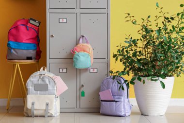 Sarı duvarın yanında okul çantalı bir dolap.